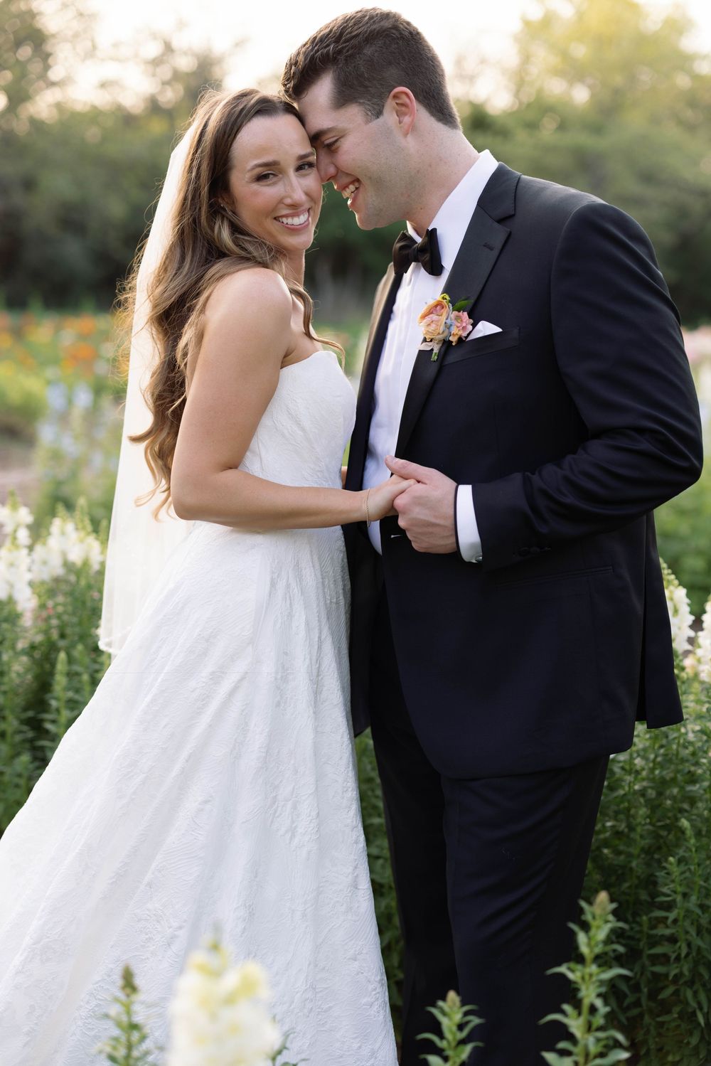 A romantic moment shared between a wedding couple in a blooming garden at sunset.