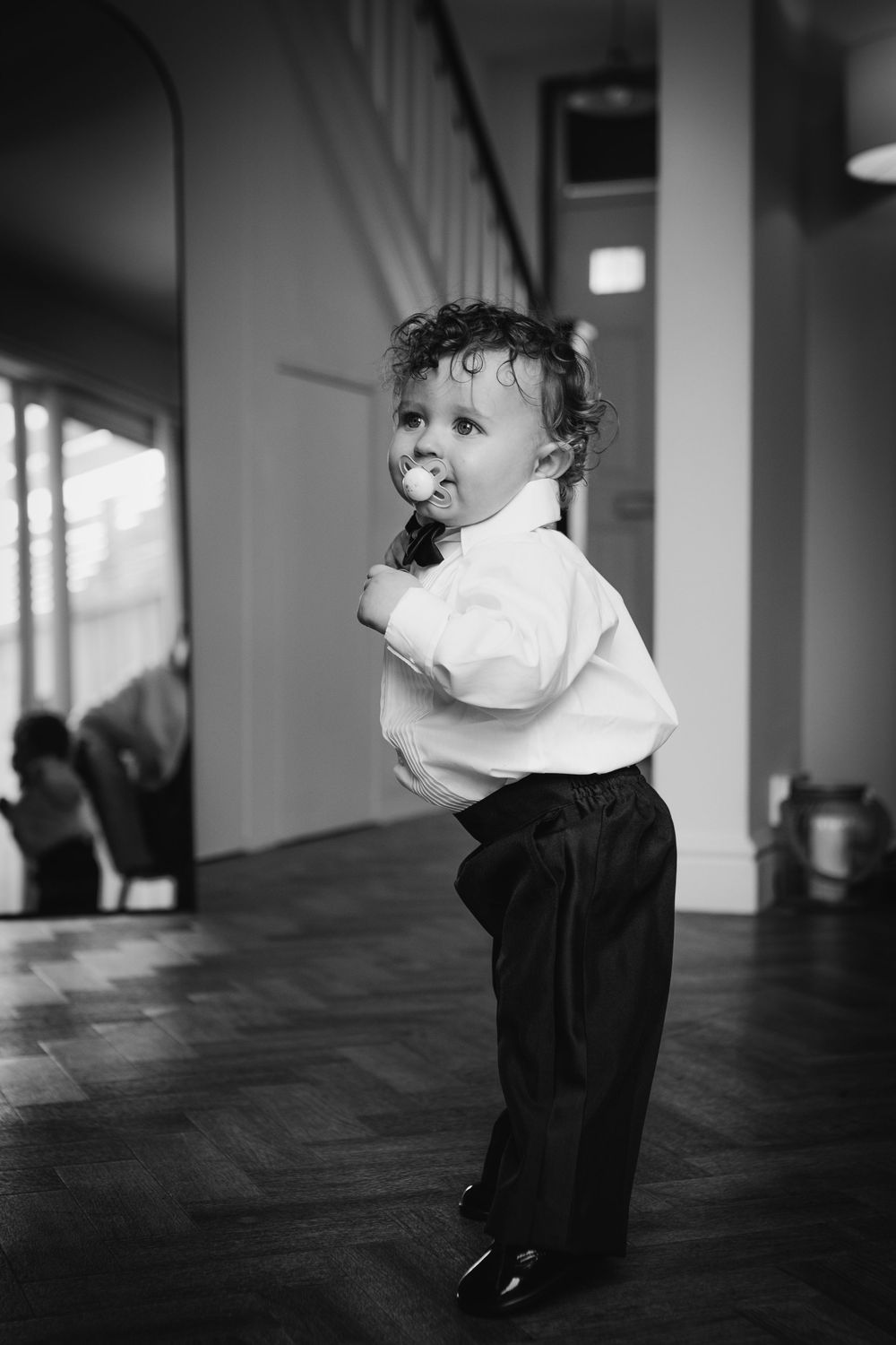 Black and white images show a small child in formal wear twirling and dancing in an interior space.