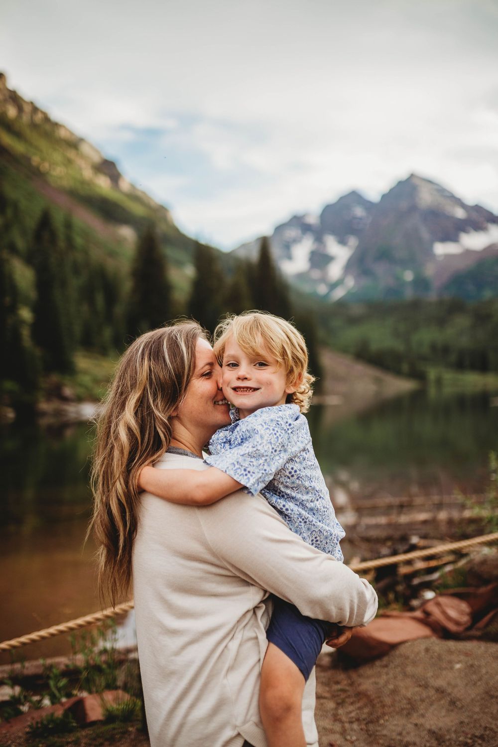 A tender embrace shared between parent and child against a stunning mountain backdrop at Maroon Bells in Colorado.