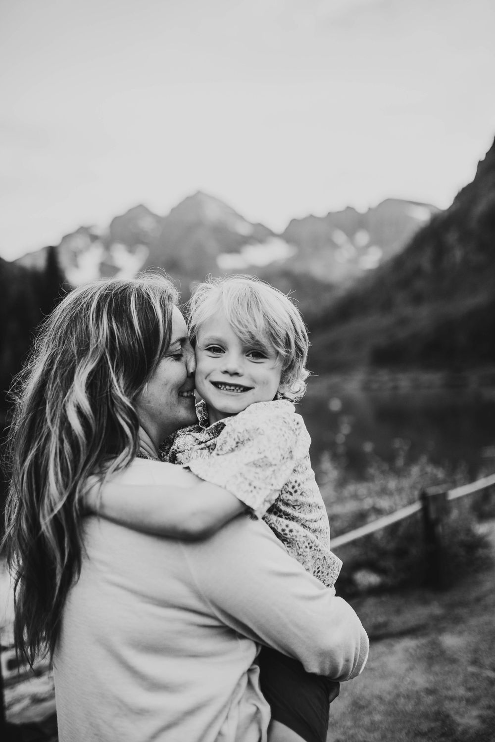 Black and white candid photo of tender family moment with mountains in background.