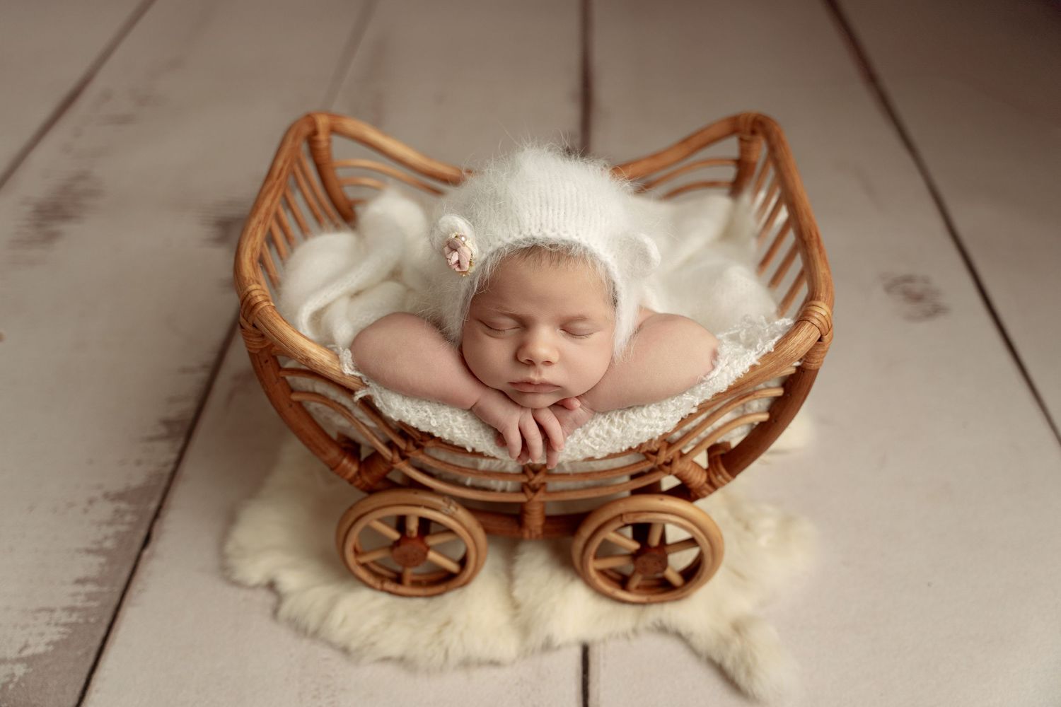 A peaceful newborn baby sleeping peacefully in cream-colored wraps and delicate headband against soft beige backdrop.