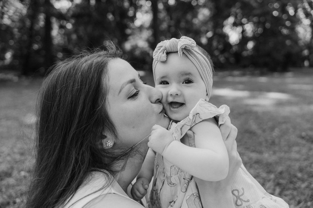 Ein zartes Schwarzweißporträt eines liebevollen Moments zwischen Mama und Baby im Freien.