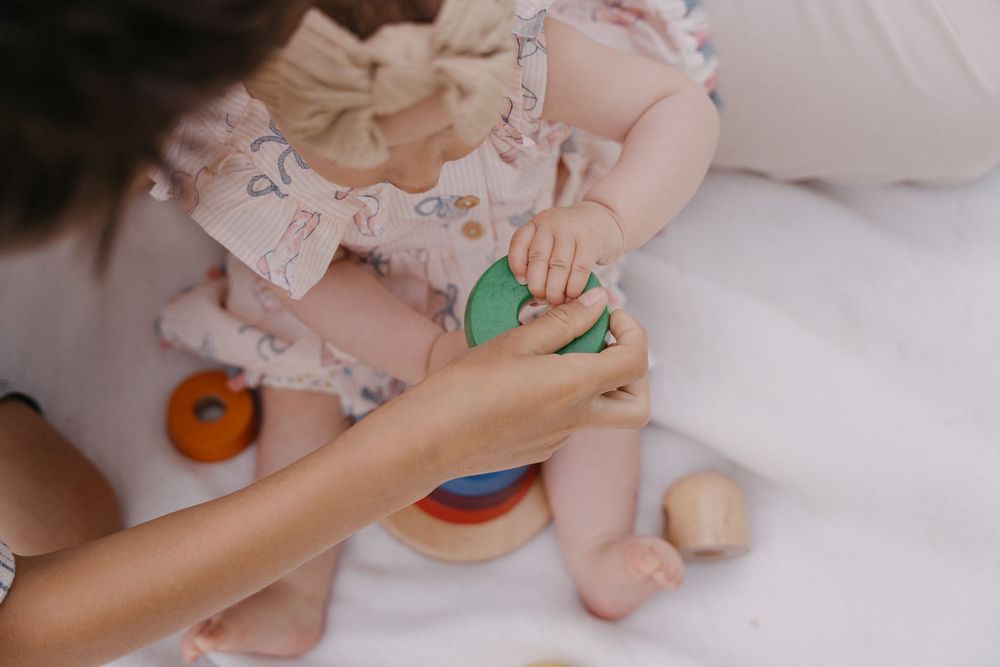 Spielmomente beim Familienshooting mit einem Kleinkind in rosa Rüschenkleidung mit buntem Spielzeug und Bauklötzen.