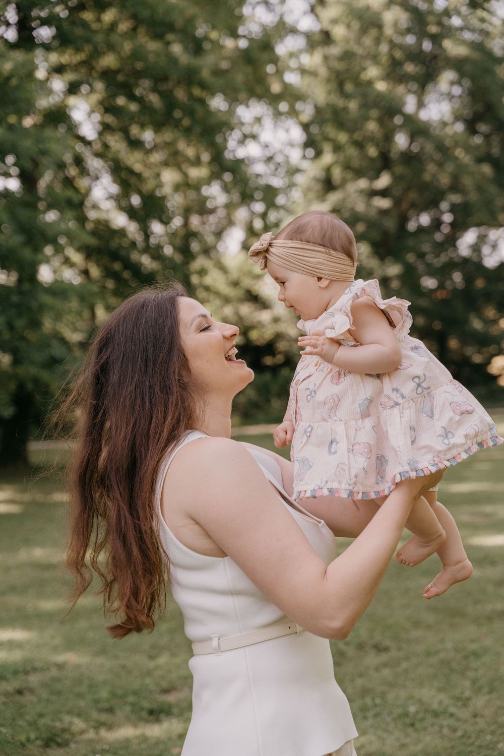 Ein fröhliches Porträt im Freien von Mama und Baby, die einen unbeschwerten Moment bei natürlichem Licht teilen.
