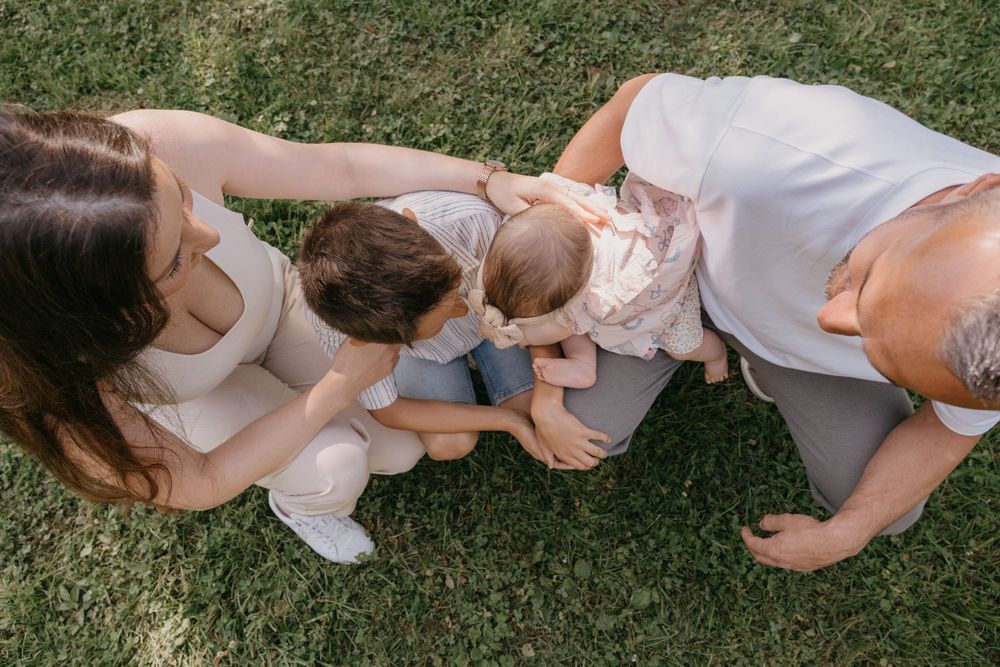 Eine Familie verbringt einen intimen Moment miteinander, während sie draußen auf dem Gras sitzt.