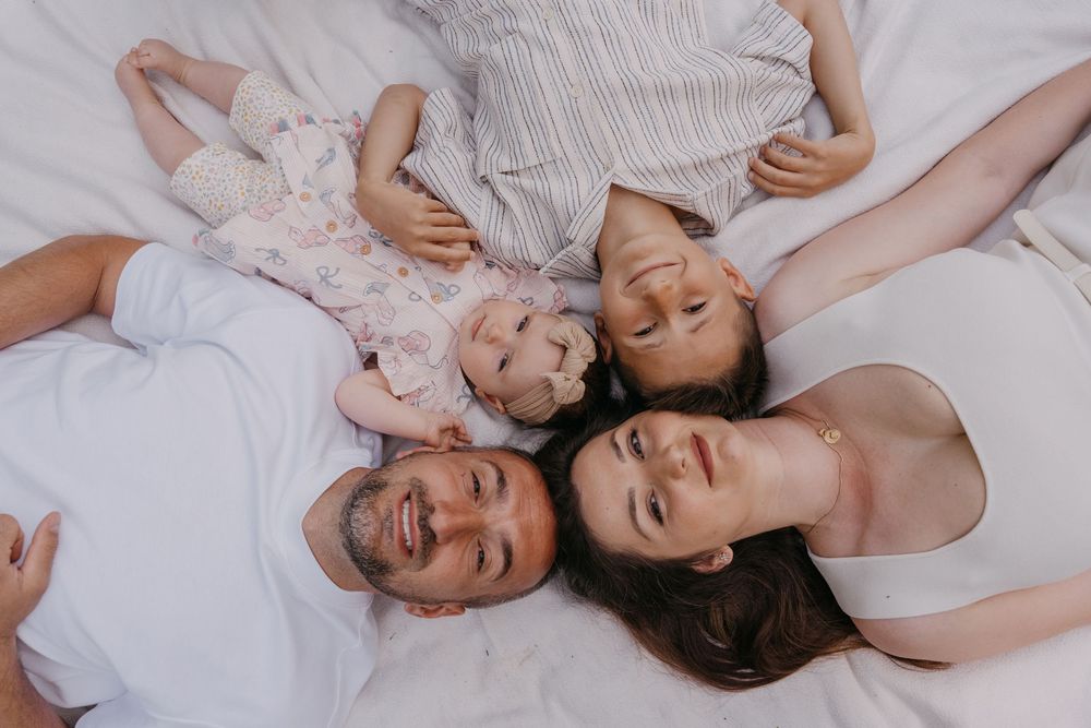 Das sind wir als Familie. Familienmoment auf weißer Decke.