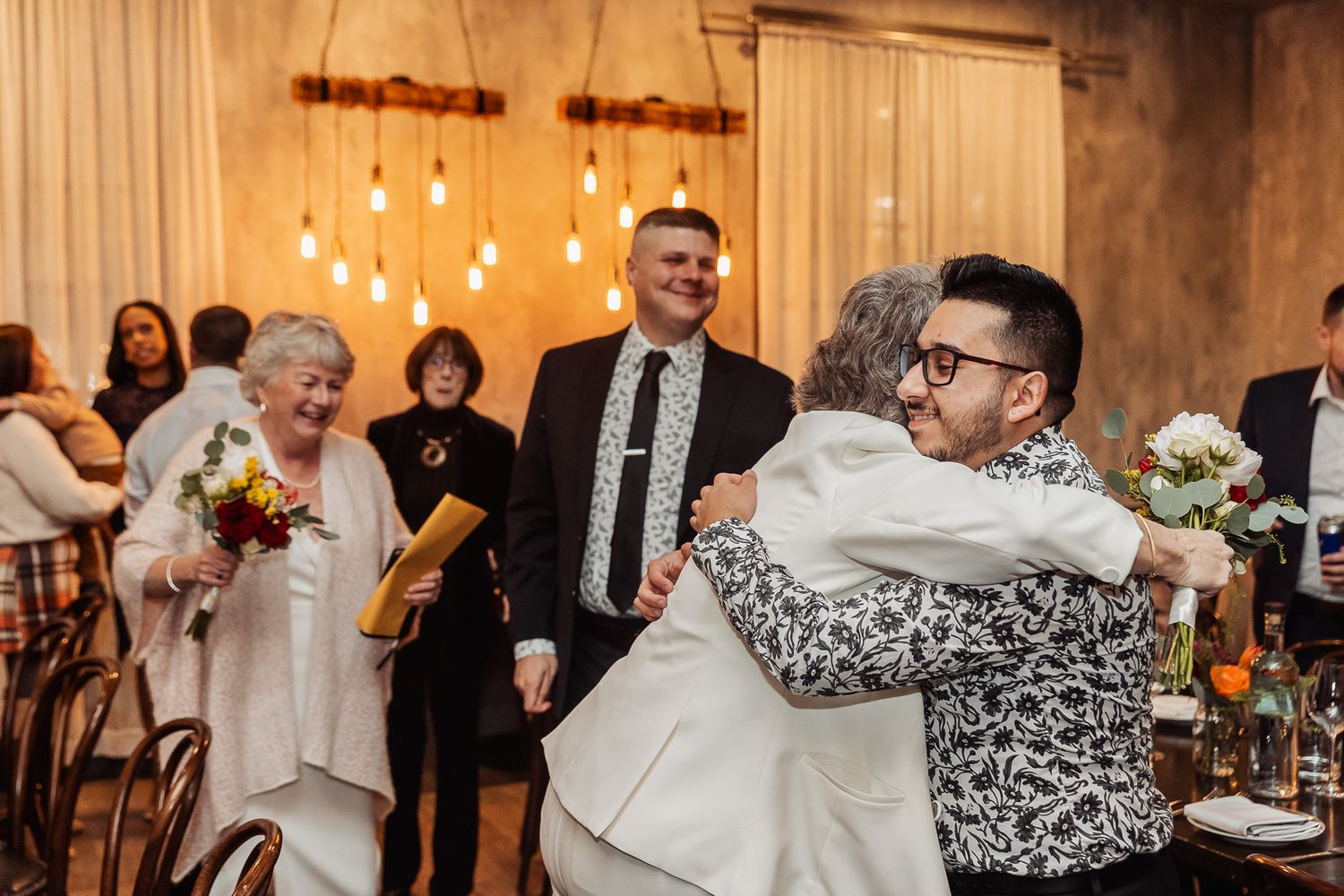 Joyful celebration moment at a wedding reception with guests embracing.