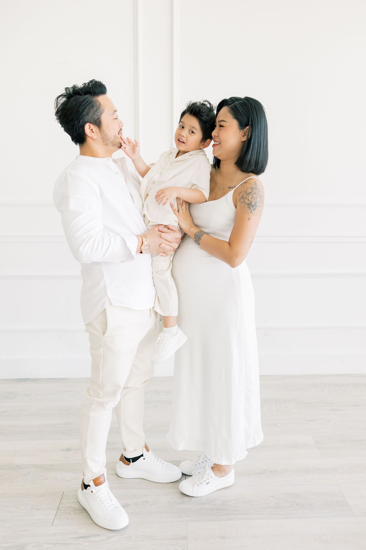 A joyful family moment shared between three people in white outfits.