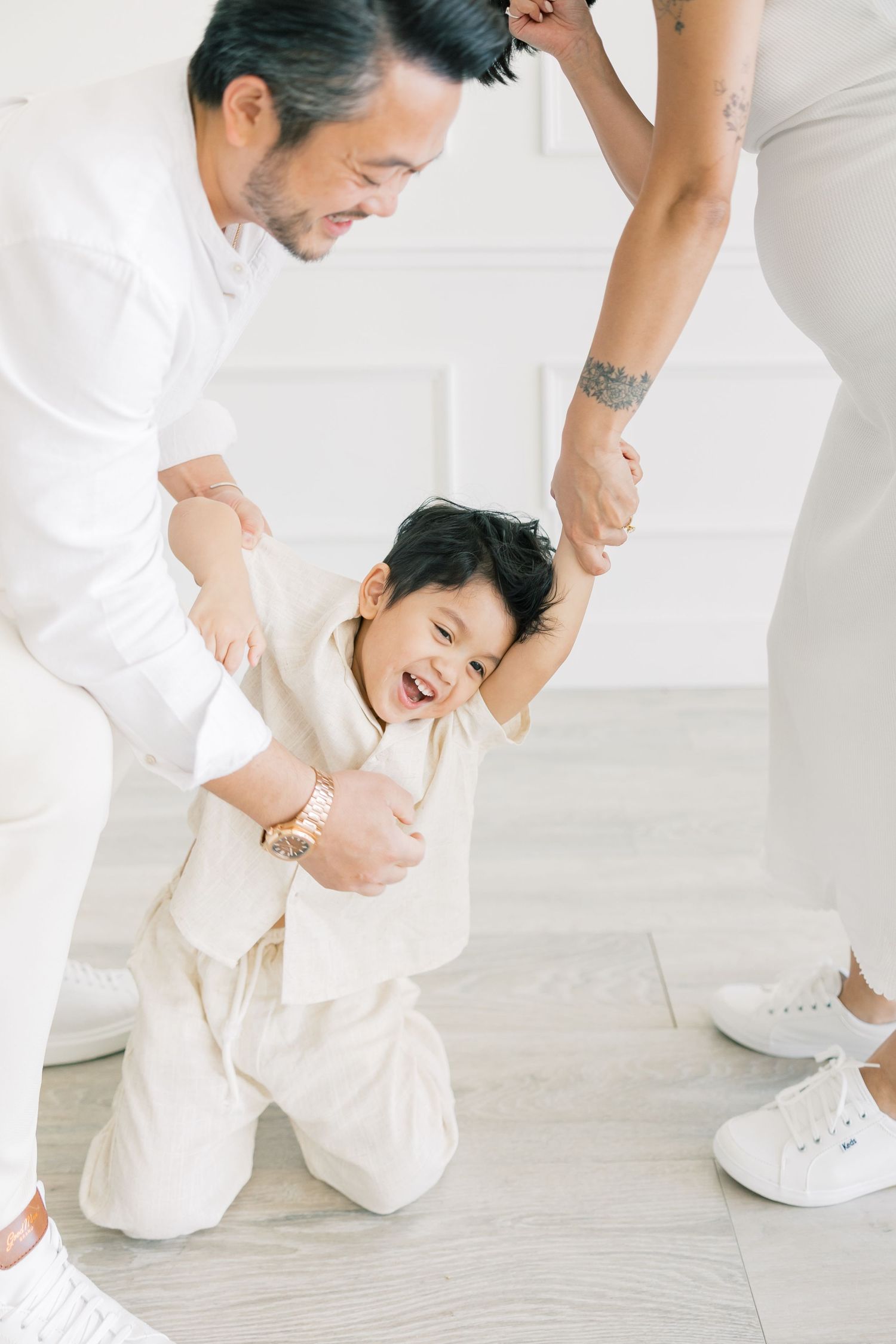 A playful family interaction captured in a bright white studio setting.