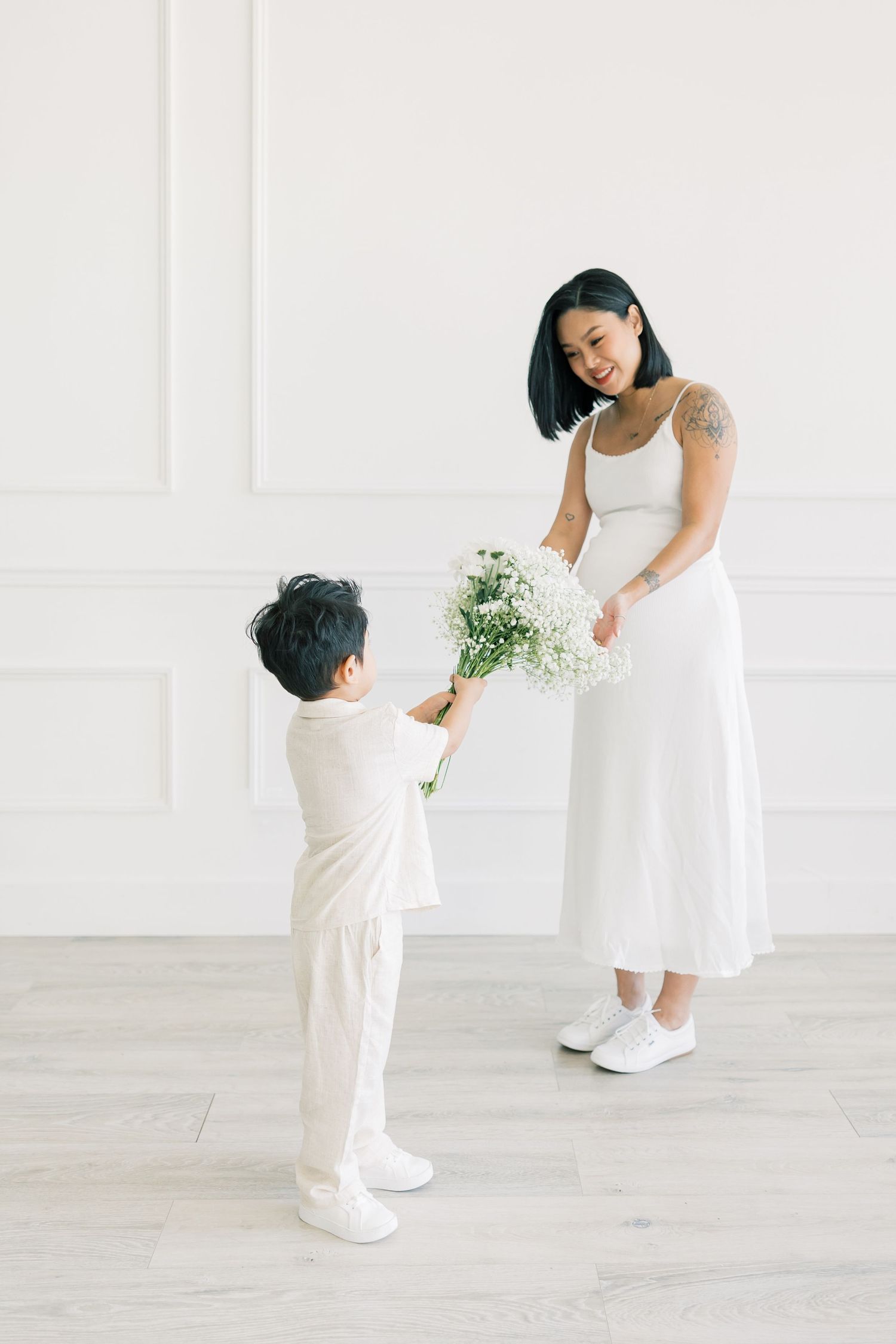 A heartwarming moment as a child in white offers flowers to someone in a flowing white dress.