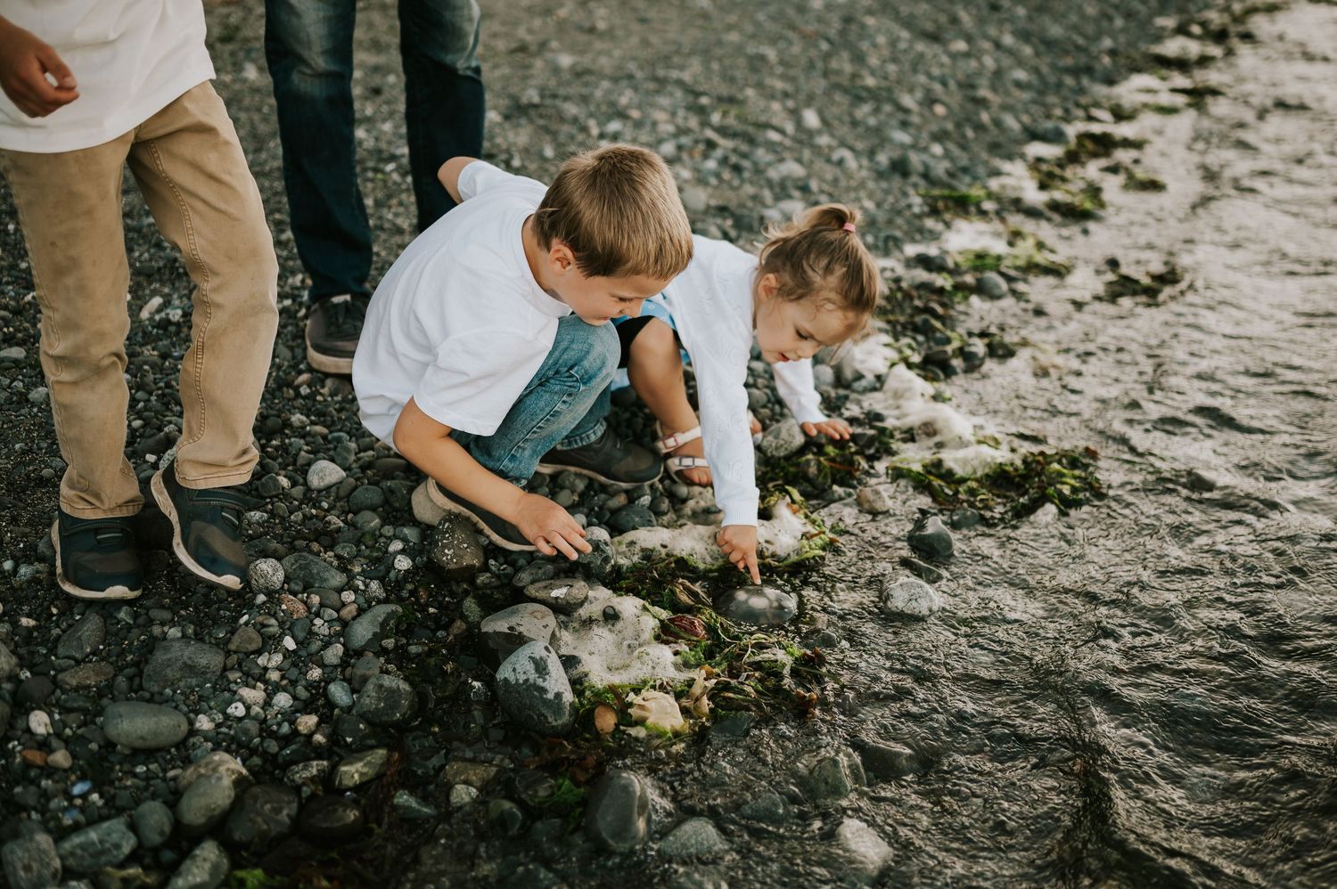 Comox Valley family photoshoot of kids candidly playing with seaweed on Kye Bay Beach. Portraits taken by photographer Soulfull Photographs