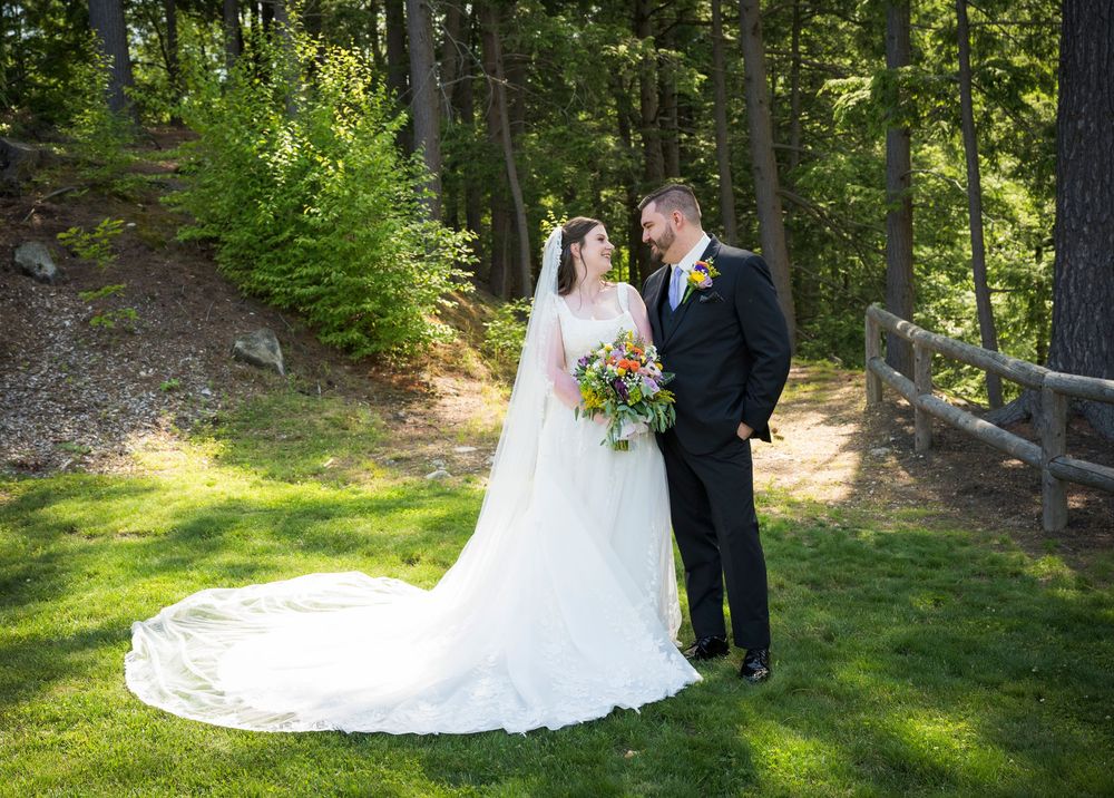 A romantic woodland wedding photo session with a couple surrounded by tall trees and dappled sunlight.