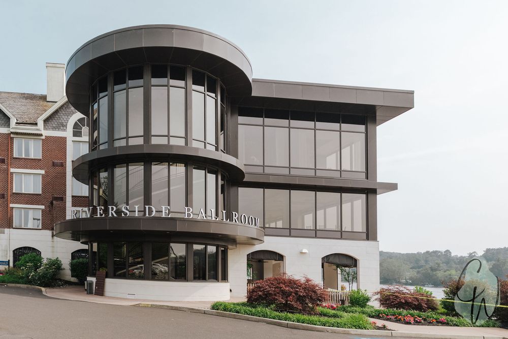 Modern commercial building exterior with curved glass windows and tiered architecture featuring landscaped gardens.