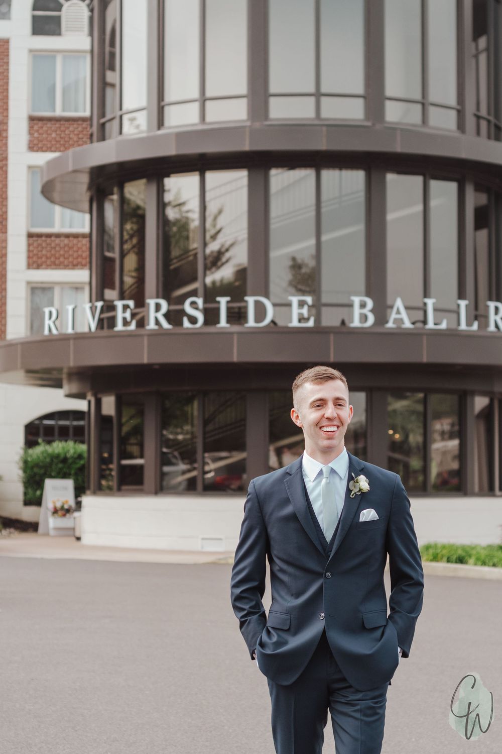 Classic groom portraits outside the Riverside Ballroom entrance in a navy suit.