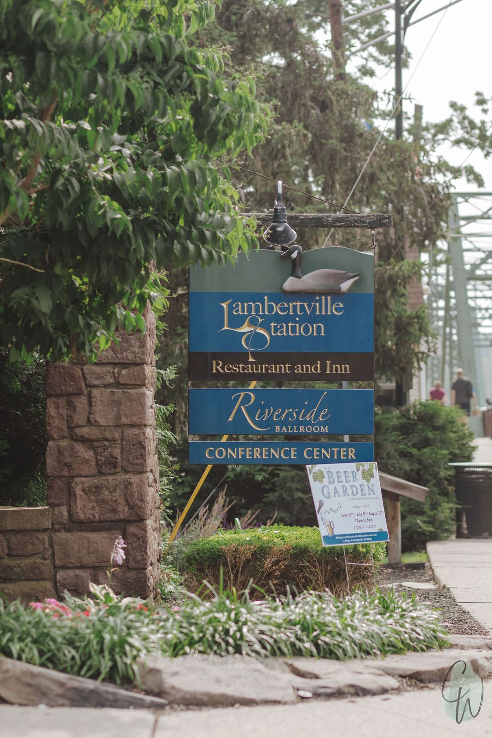 A long row of brown stone pillars and signage for 'Lambertville Station Restaurant' along a landscaped walkway.
