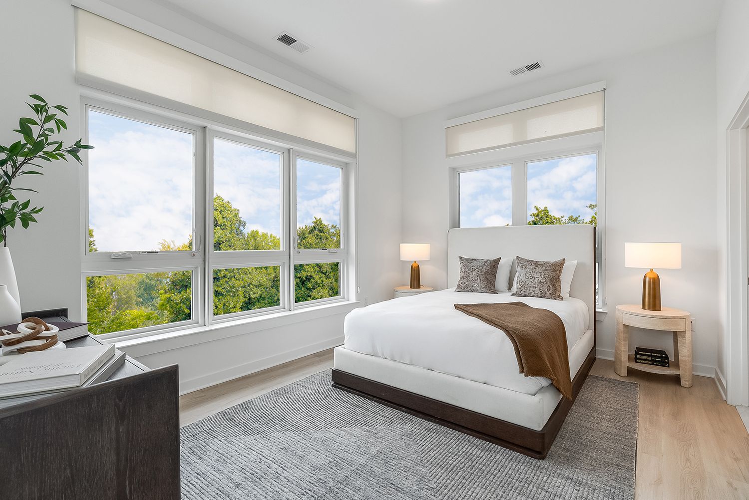 Modern bright bedroom design featuring minimalist furniture and large windows letting in natural light.