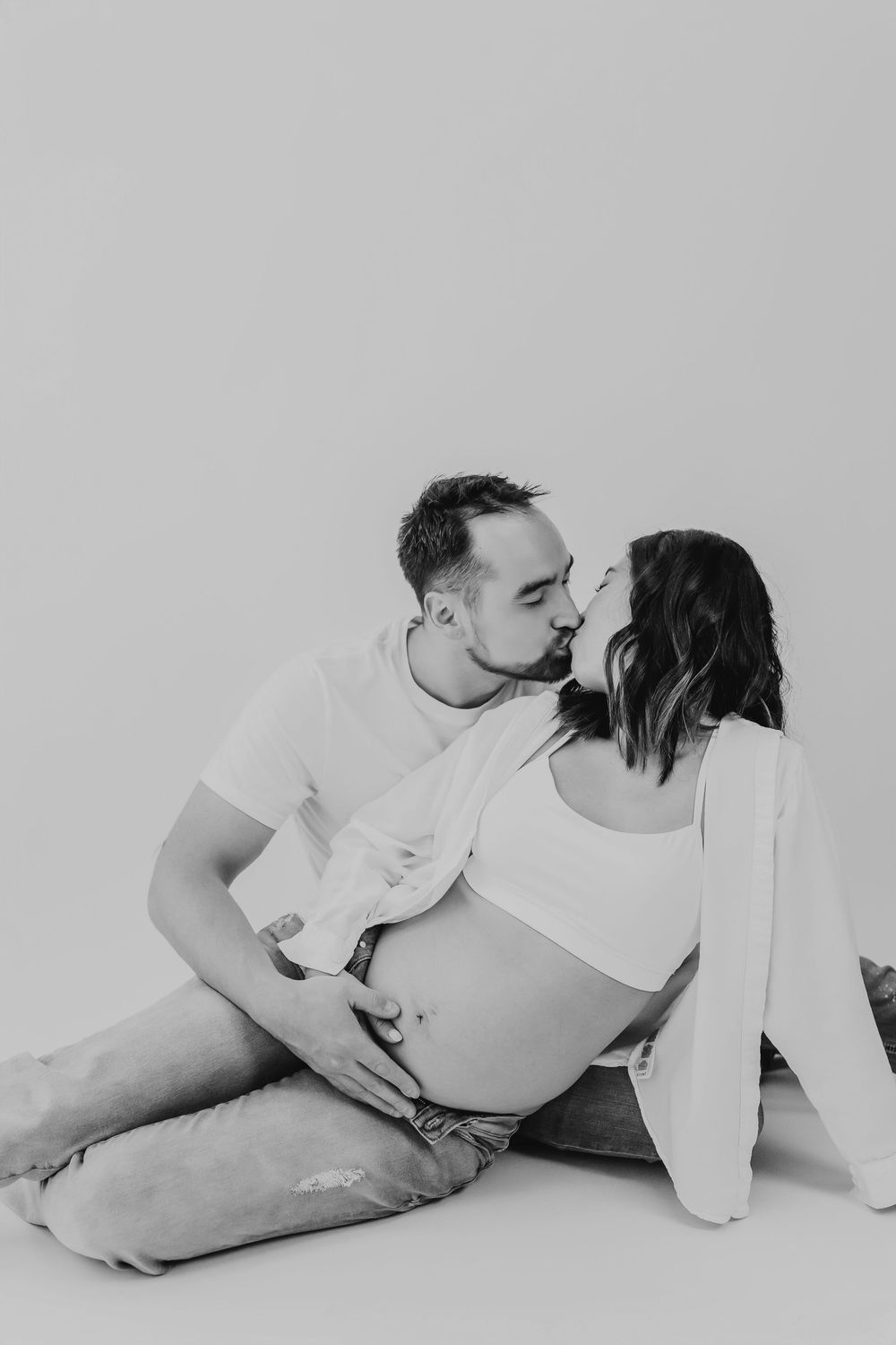 Couple laying on white surface together in black and white photography series.