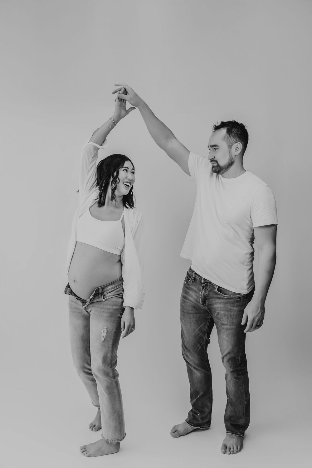 Couple photographed in minimalist studio setting wearing casual attire in black and white.