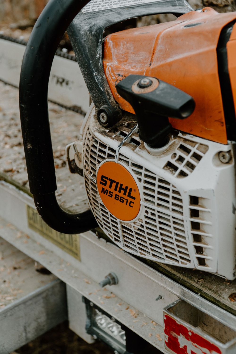 Close-up view of a Stihl chainsaw motor housing with orange and white coloring.