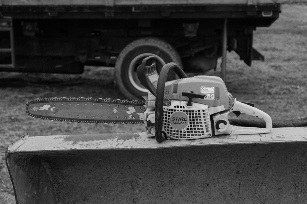 Black and white image of a chainsaw resting on metal equipment.