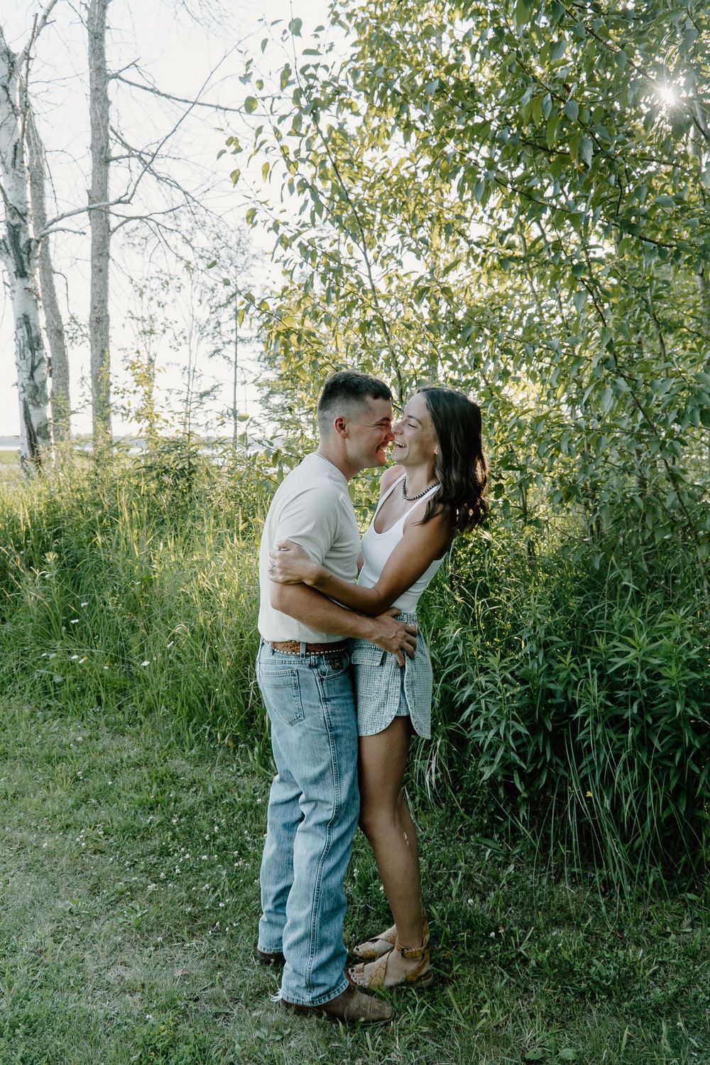 A romantic couple embracing in a sunlit forest setting.