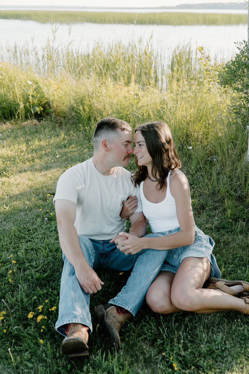 A couple sharing an intimate moment while sitting by a lakeside.
