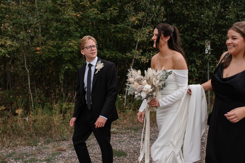 A couple shares a candid moment with guests during their outdoor wedding ceremony in a natural setting.