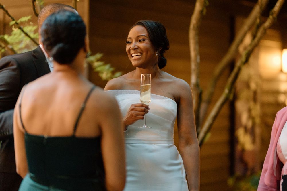 A joyful moment at a wedding reception as someone in a white strapless gown raises a champagne glass in celebration.