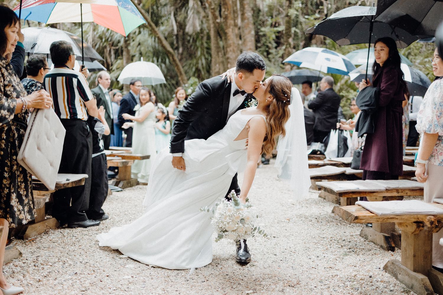 A romantic dip-style kiss at an outdoor wedding ceremony captured by Apertured Media Auckland Wedding Photographer.