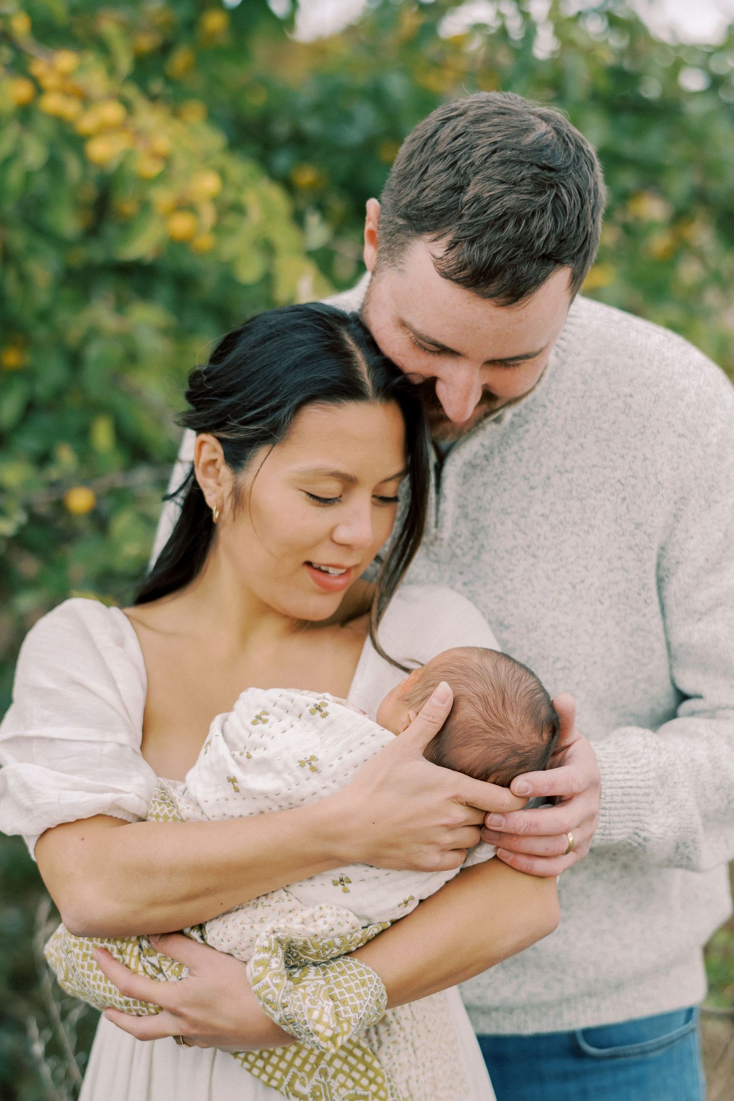 Loving family moment outdoors with parents cradling their newborn baby.