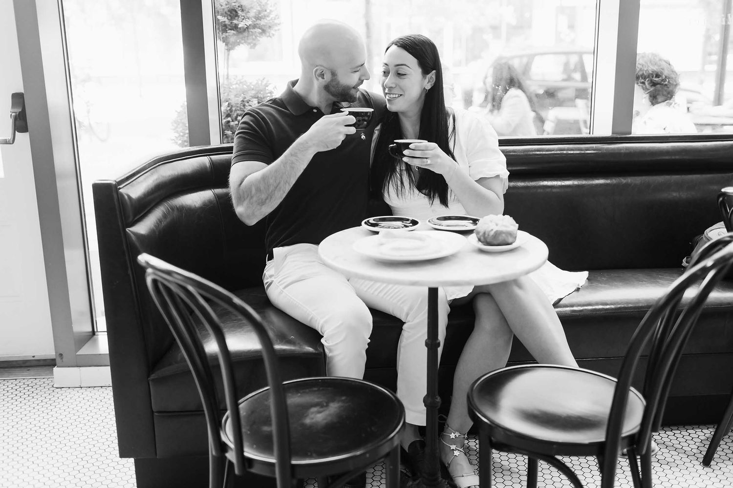 The loving couple share a cup of coffee during this Boston engagement session held in a cafe in a Seaport district.