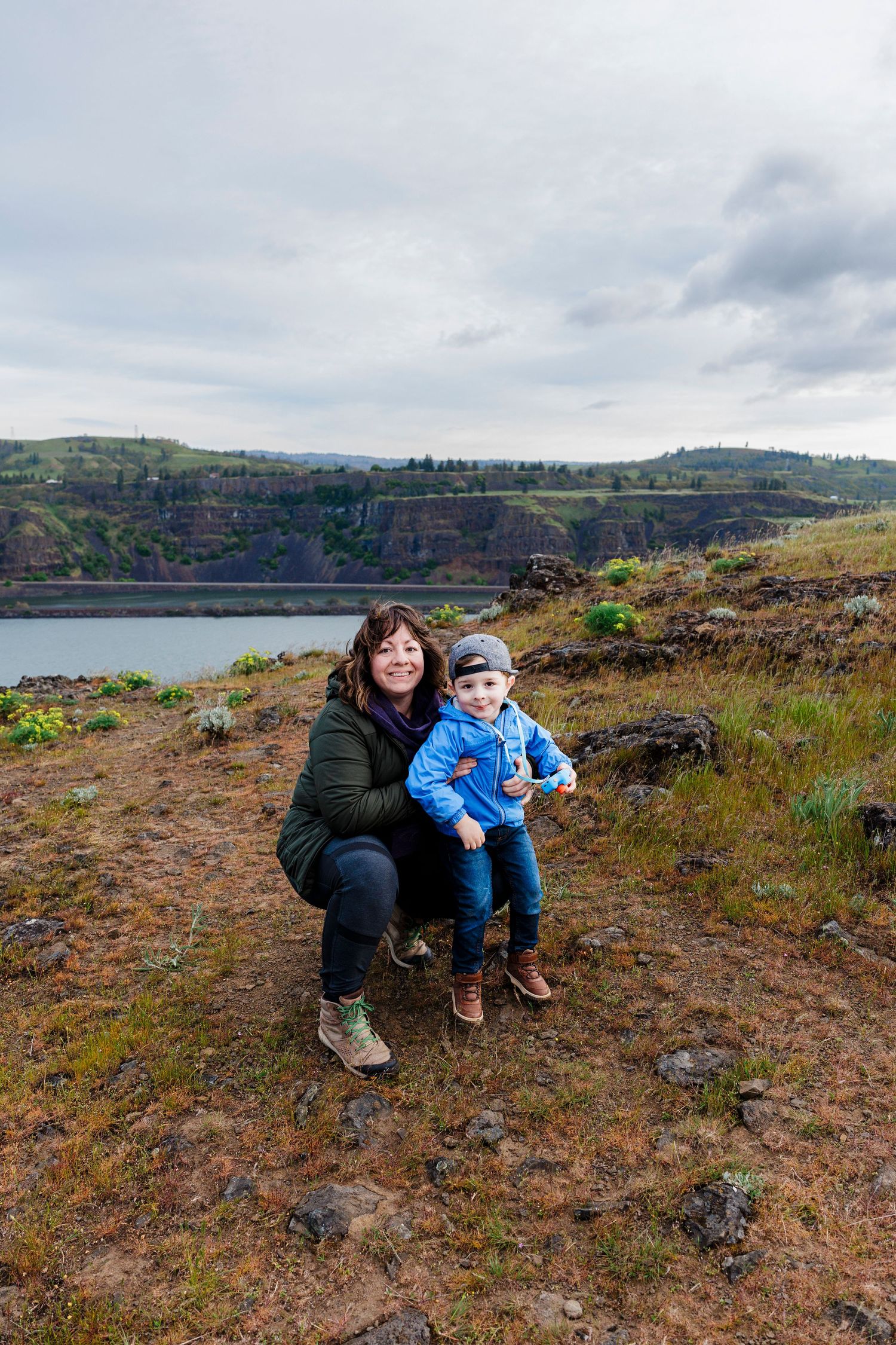 Scenic viewpoint overlooking Columbia River Gorge with two people enjoying dramatic landscape and cloudy skies.