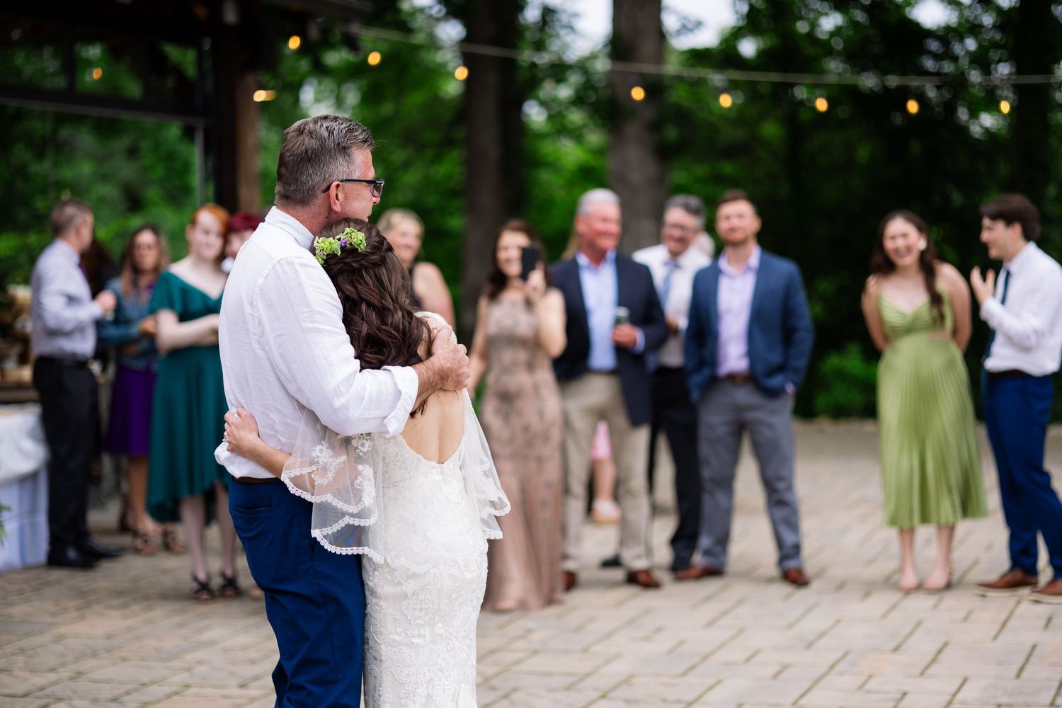 A newlywed couple dances outdoors surrounded by guests at a festive garden wedding reception.