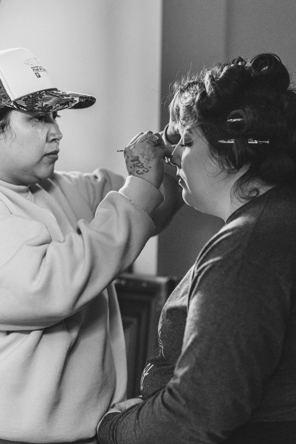 Four sequential black and white shots capture a tender moment as guests get ready for a wedding celebration.