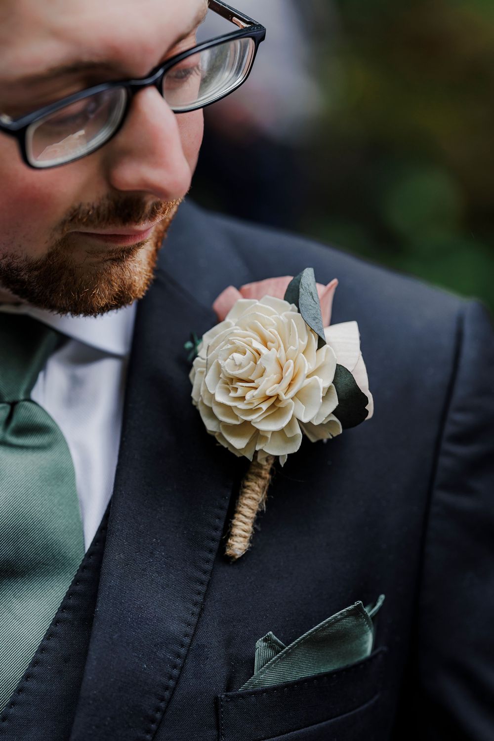 Close-up detail of a white floral boutonniere with twine wrapping on a dark suit lapel.