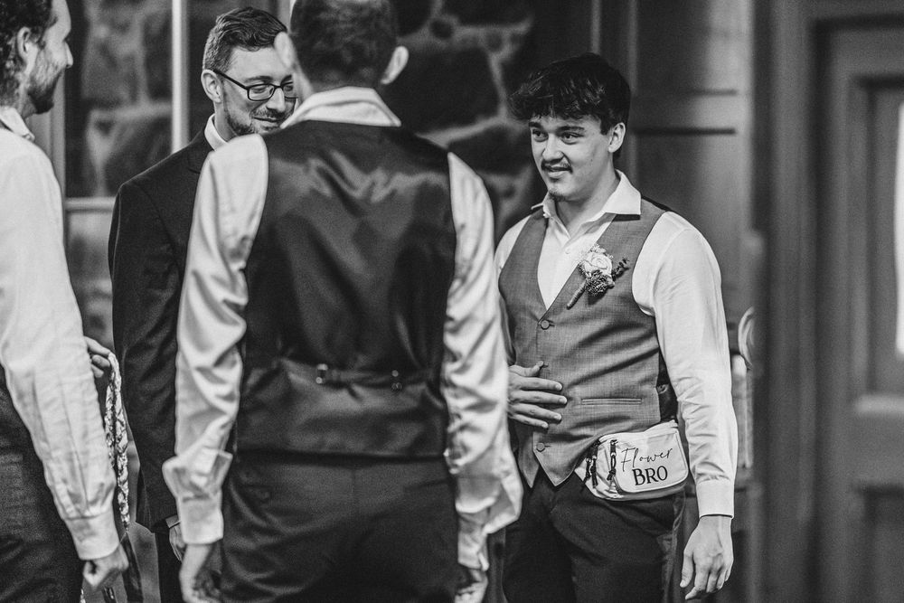Wedding party members share laughter and conversation in formal attire at an event.