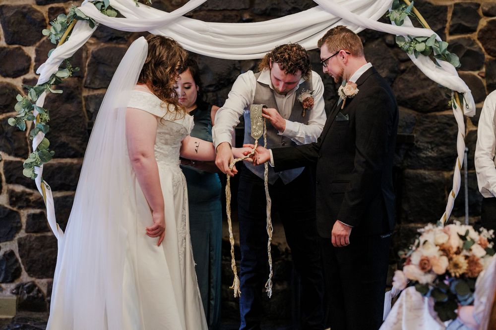 White fabric draped elegantly over a wedding ceremony arch with natural greenery accents.