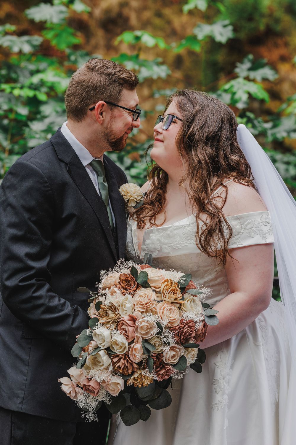 Wedding couple share a joyful moment together while holding a peach and cream bouquet.