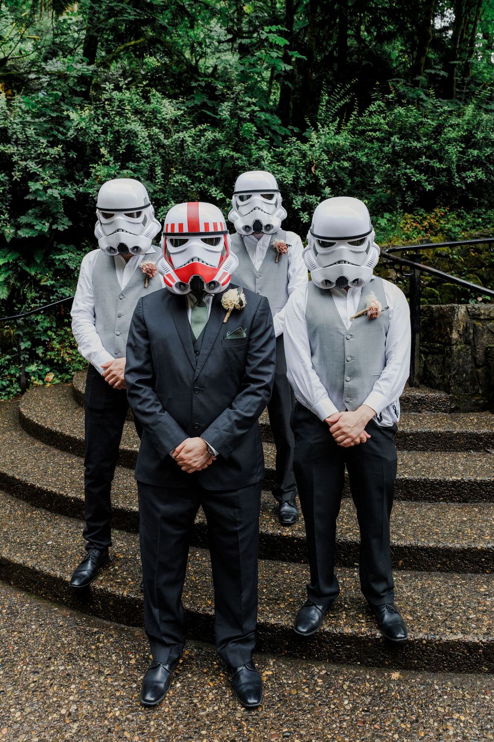 Wedding party members wearing Star Wars Stormtrooper helmets pose for formal photos.