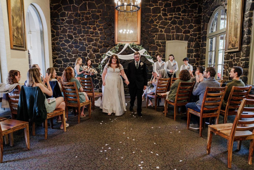 Indoor wedding reception venue with stone walls and wooden chairs decorated for celebration.