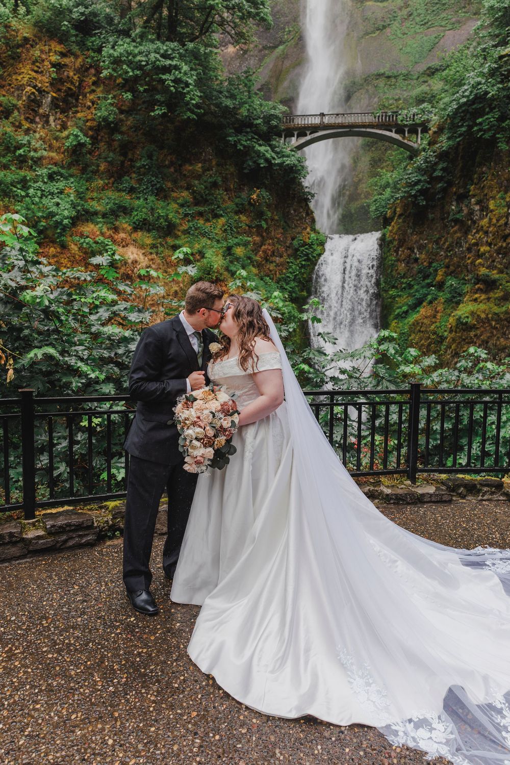 Dramatic wedding photos taken by a cascading waterfall with flowing white dress and autumn foliage.