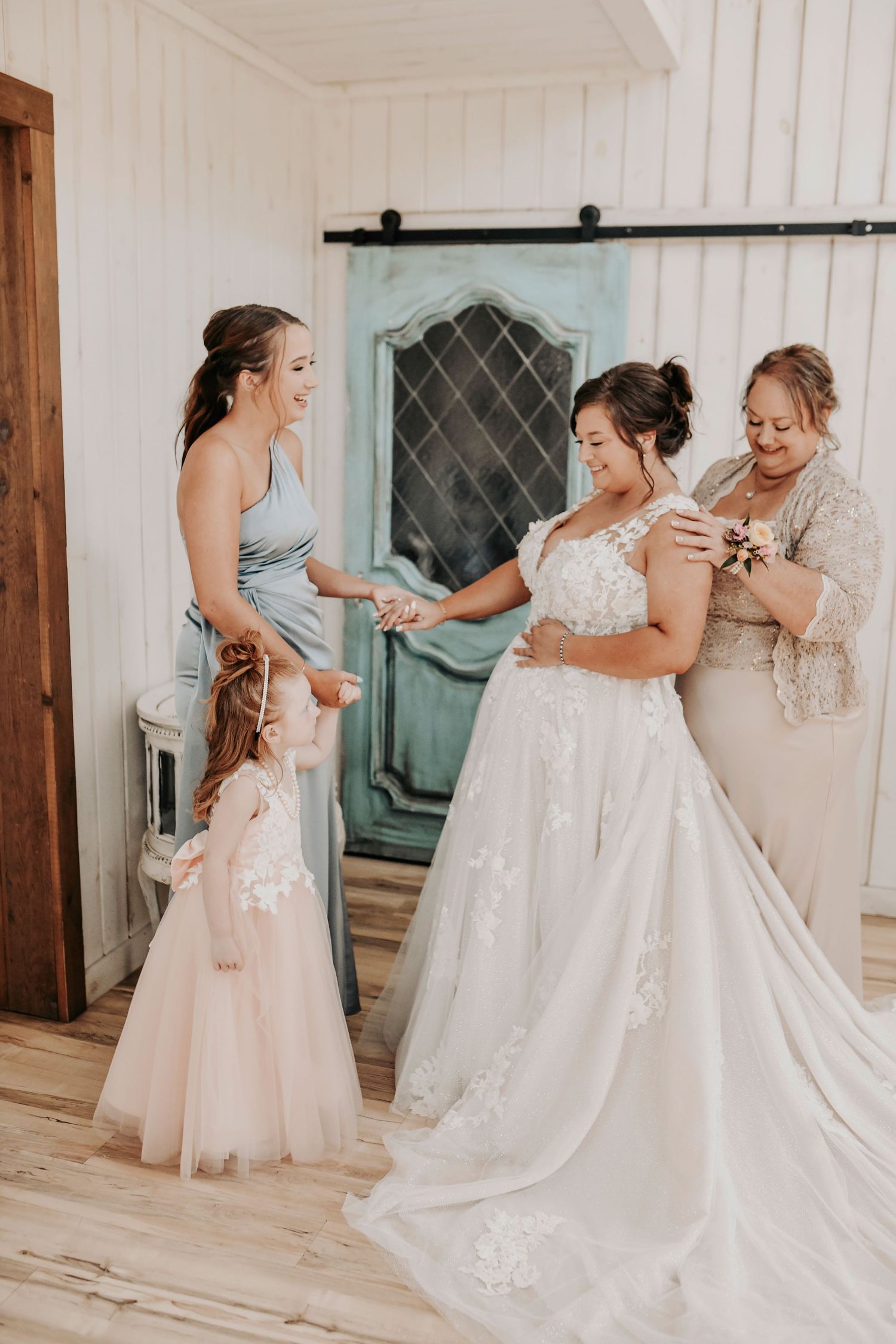 Bride, sister, and daughter sharing a joyful moment during hair and makeup