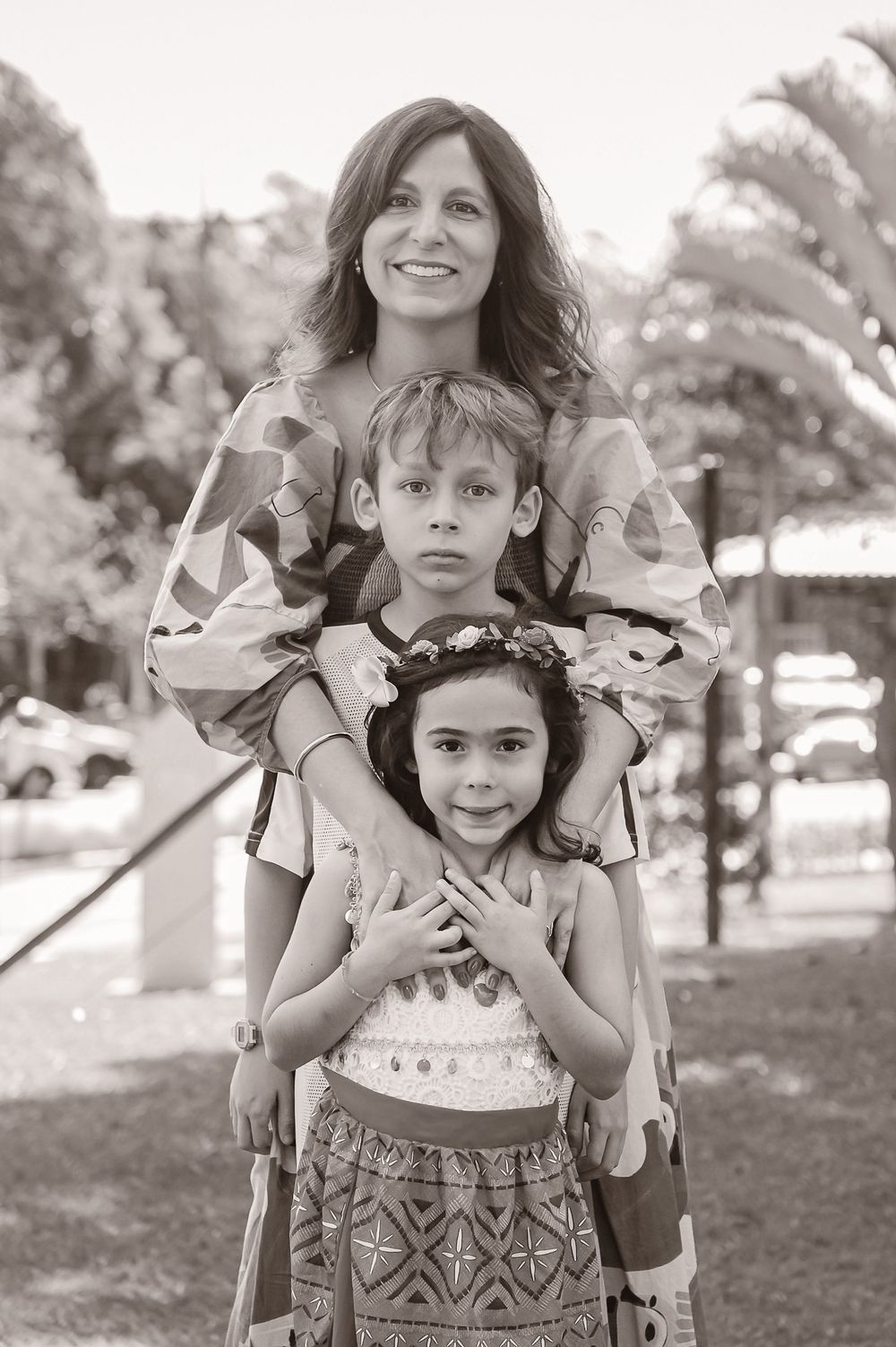 A series of four candid black and white photographs showing playful mother-daughter moments in a park setting.