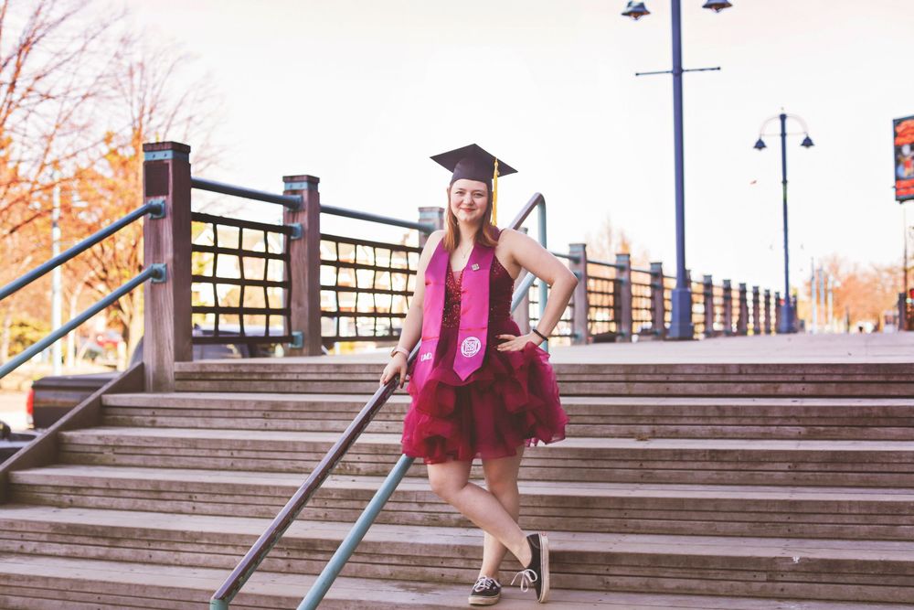 Person in burgundy dress walking down concrete steps with metal railings during autumn season.