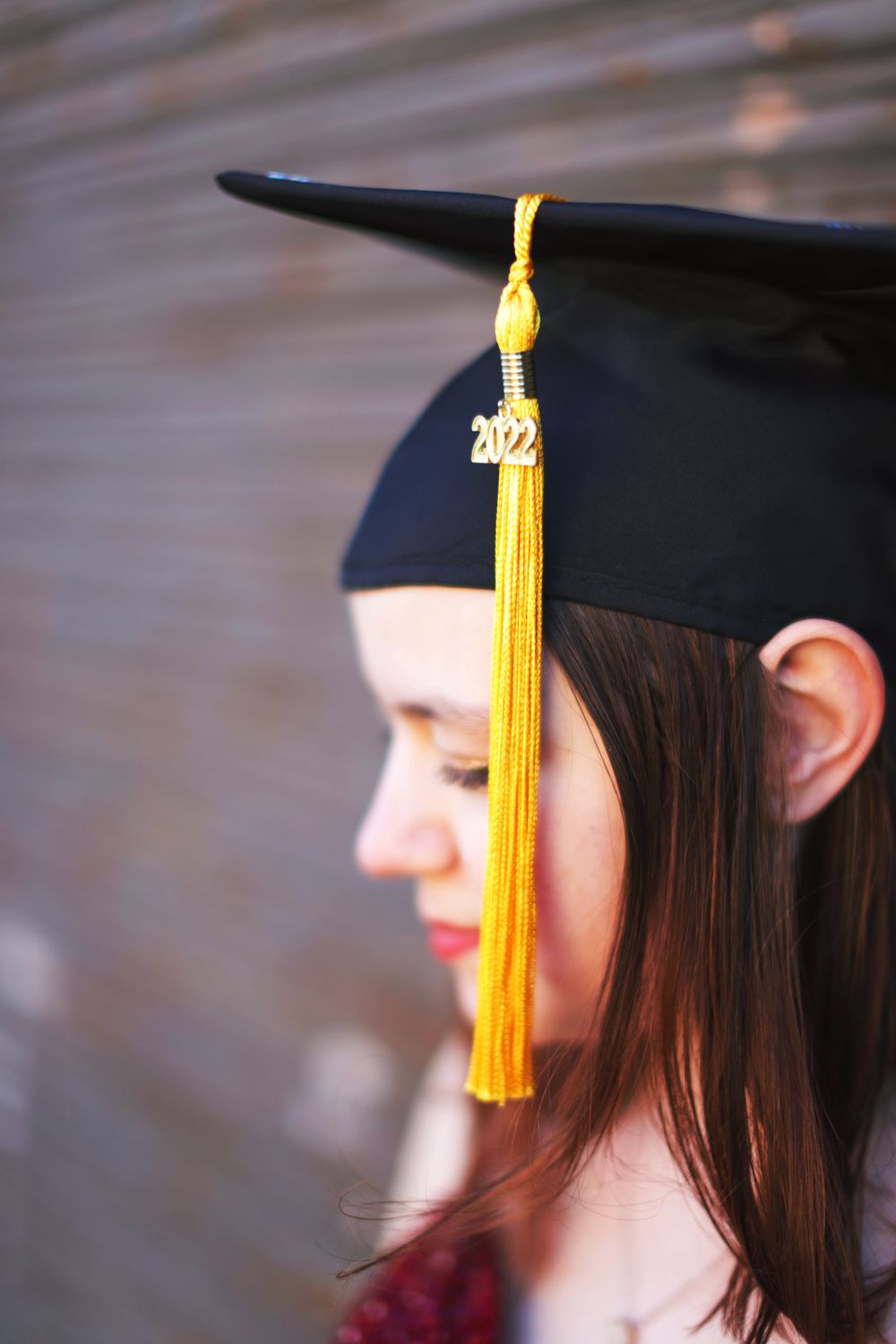 A graduation cap with gold 2022 tassel photographed in profile against a blurred background.