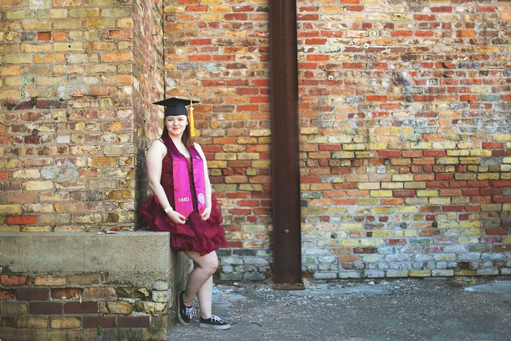 Graduate in a magenta cap and gown poses against a rustic brick wall backdrop in a series of related shots.