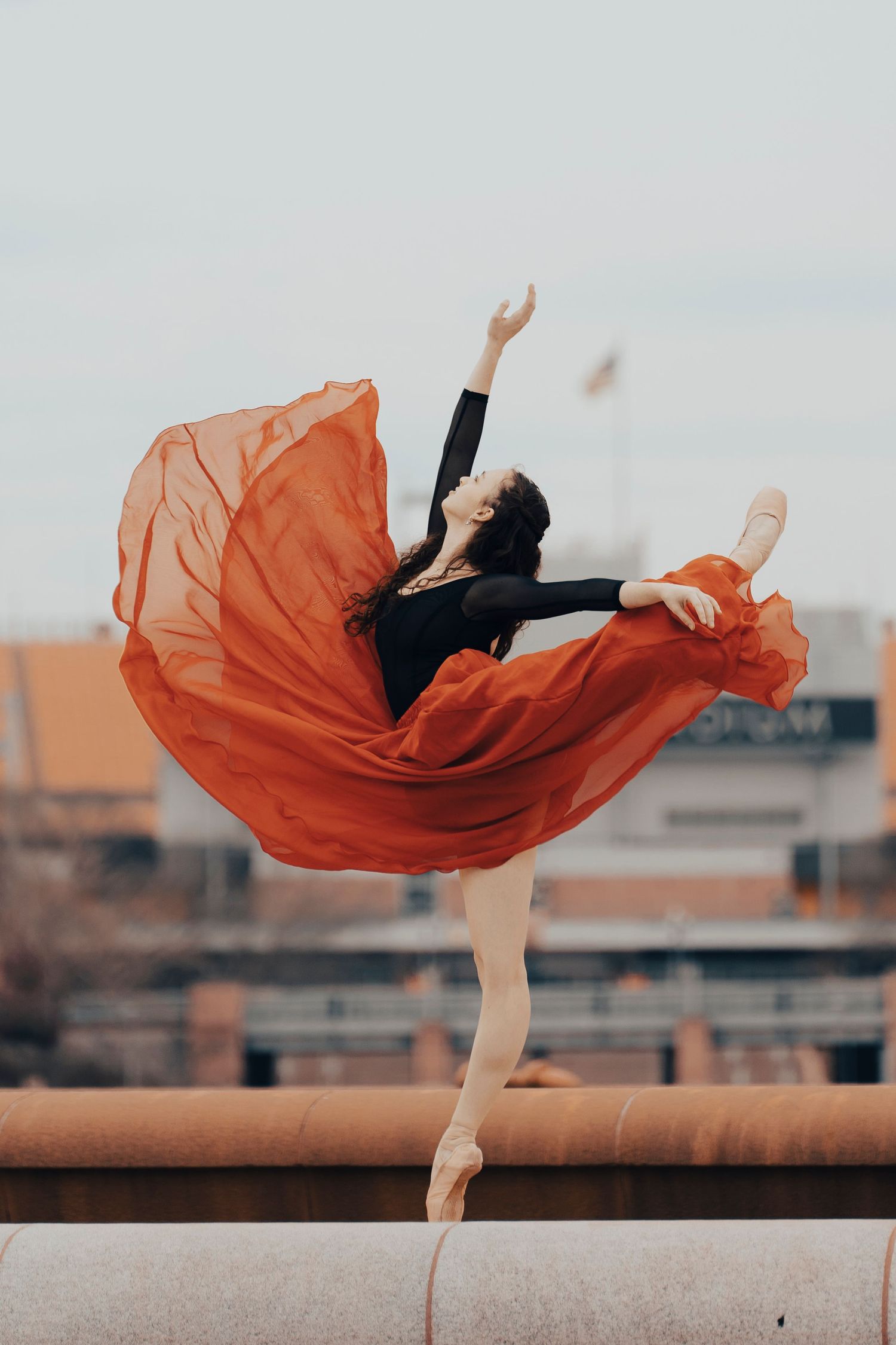Ballerina performing attitude at Point State Park with golden hour light reflecting off the river in Pittsburgh