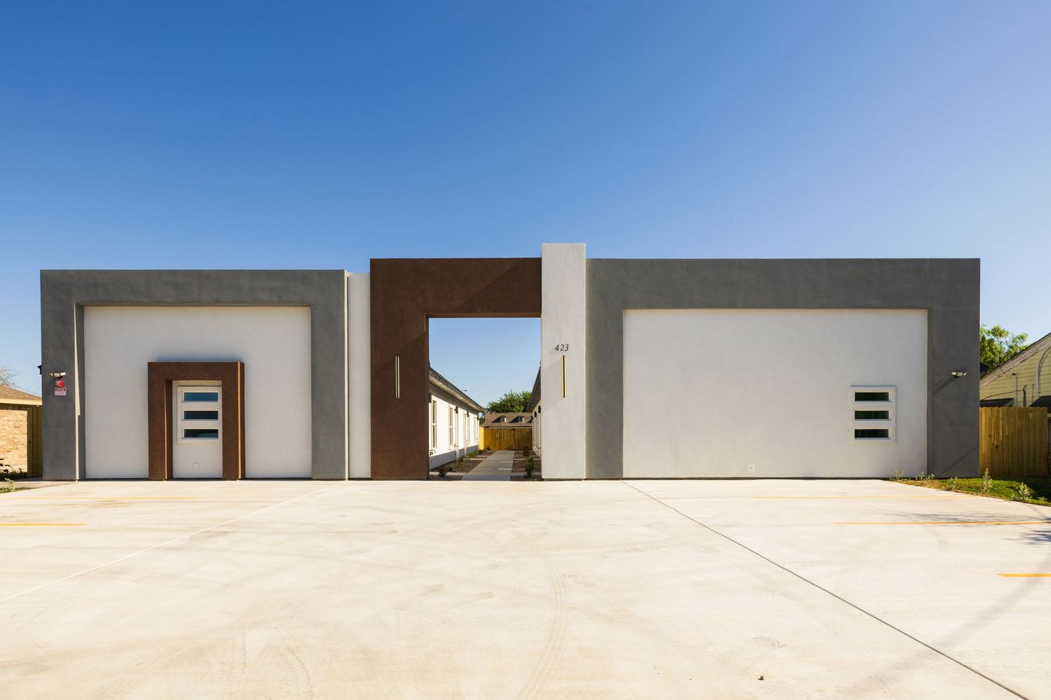 Modern minimalist garage doors with small square windows and clean lines against a white stucco exterior.
