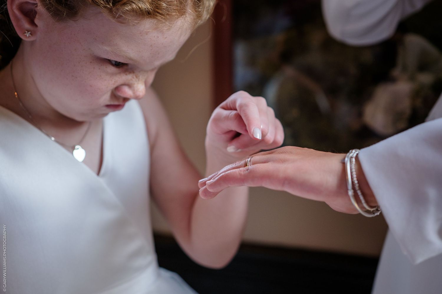 A small hand gently touches another person's palm, with one wearing a bracelet in a tender moment during an event.