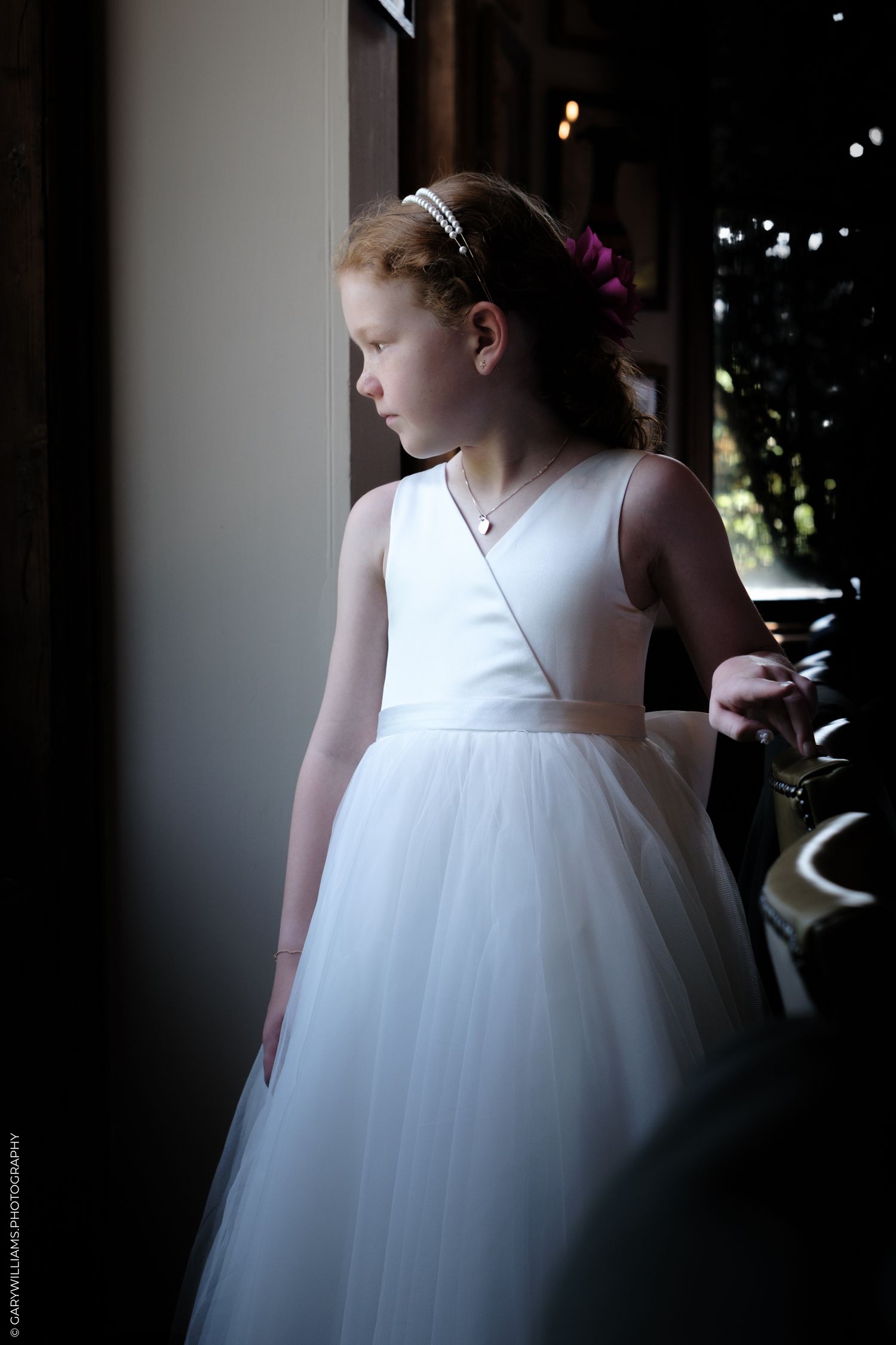 A silhouetted figure in a flowing white dress stands by a window, creating a dramatic backlit profile effect.